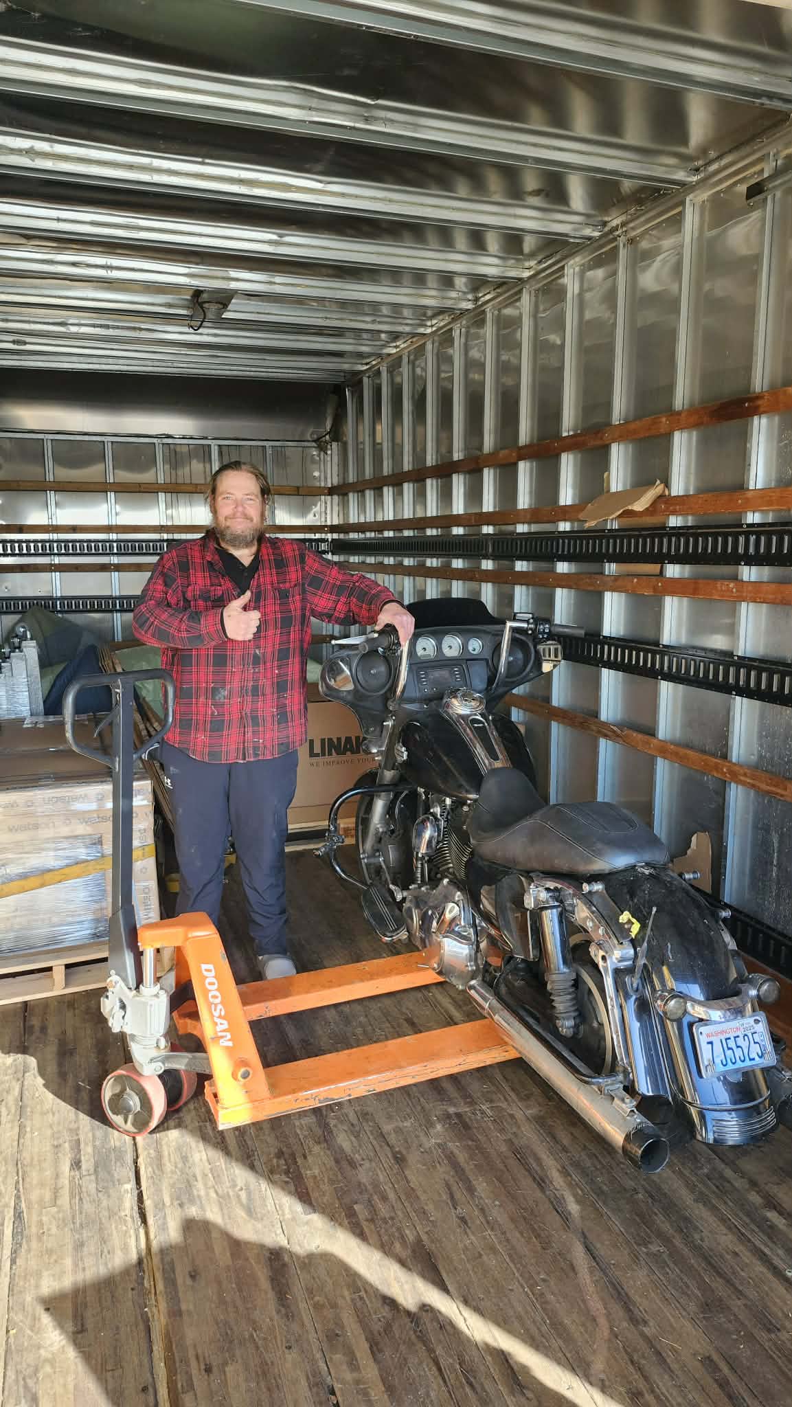 Crew member with a motorcycle secured on a pallet in the moving truck
